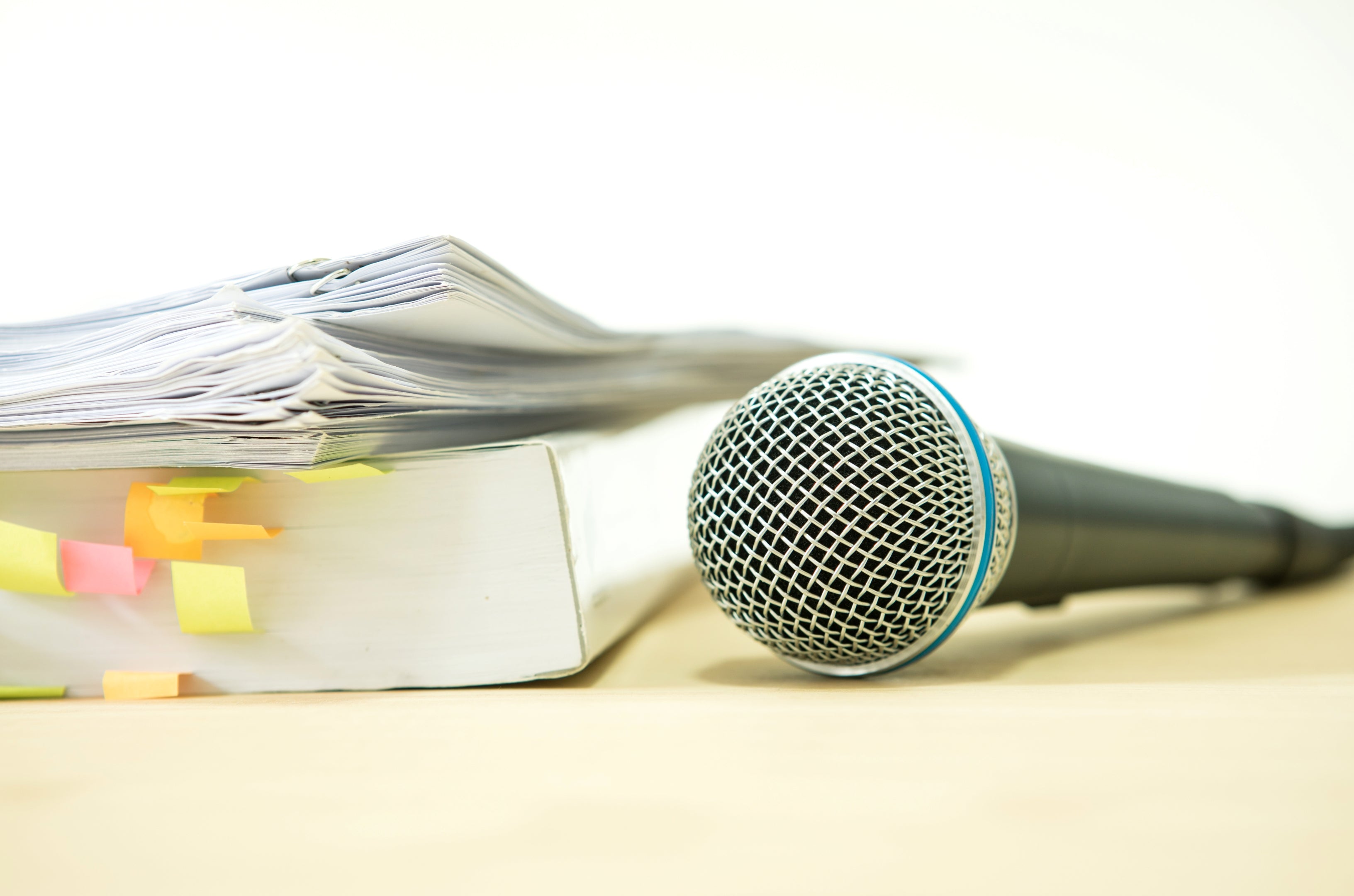Microphone next to a stack of papers with colorful markers on a light background